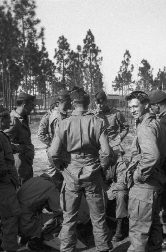 Richard Winters (facing the camera in the back) teaching his soldiers to pack their parachutes. Skip Muck is the man on the right looking at the camera.
