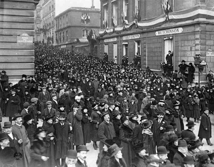 At the corner of Avenue des Champs-Elysées and Rue Balzac in Paris, the crowd awaits the parade of 200,000 civilians and soldiers in the afternoon of Sunday, November 17 1918