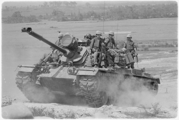 Marines of E Company, 2nd Battalion, 3rd Marines, riding on an M48A3 tank
