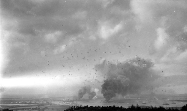 Panorama view of Pearl Harbor, during the Japanese raid on 7 December 1941, with anti-aircraft shell bursts overhead.