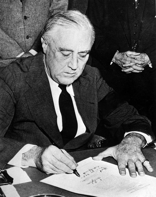 President Roosevelt, wearing a black armband, signs the Declaration of War on Japan on December 8, 1941.