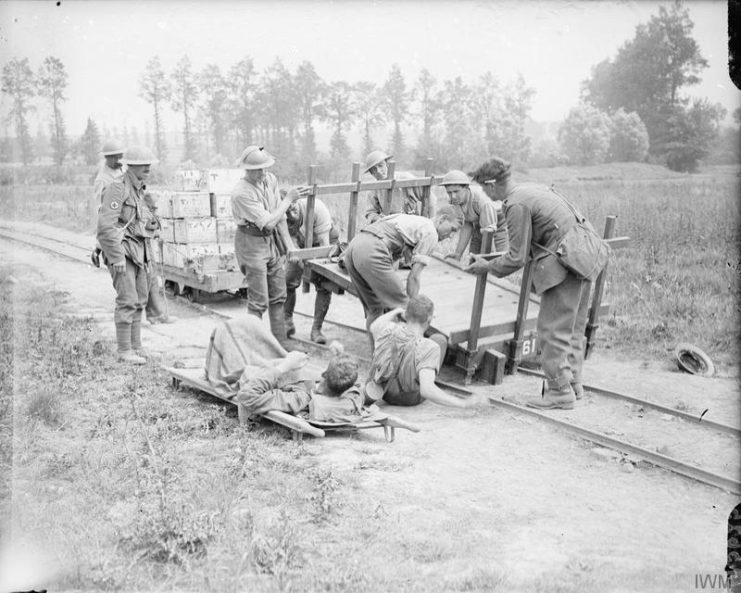 A derailed light railway trolley used for conveying wounded is being replaced. Behind it is a ration trolley. Near Kemmel, June 10, 1917.