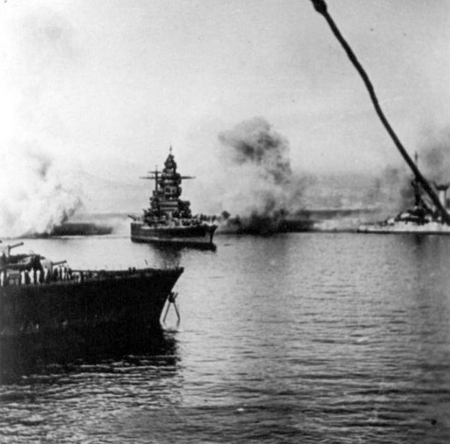 Battleship Dunkerque, under fire during Operation Catapult Comment – it might be Strasbourg, with two-level bridge. By Jacques Mulard – CC BY-SA 3.0.