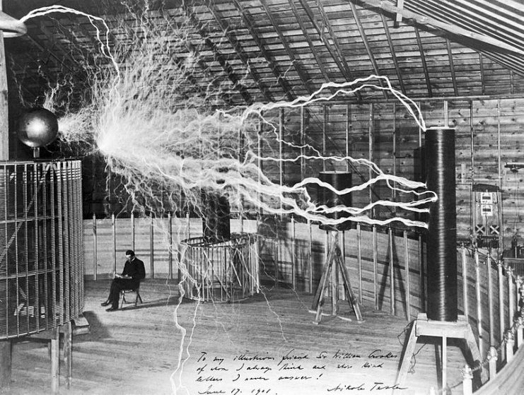 Serbian-American inventor Nikola Tesla in his laboratory in Colorado Springs around 1899, supposedly sitting reading next to his giant “magnifying transmitter” high voltage generator while the machine produced huge bolts of electricity.Photo: Fæ CC BY 4.0