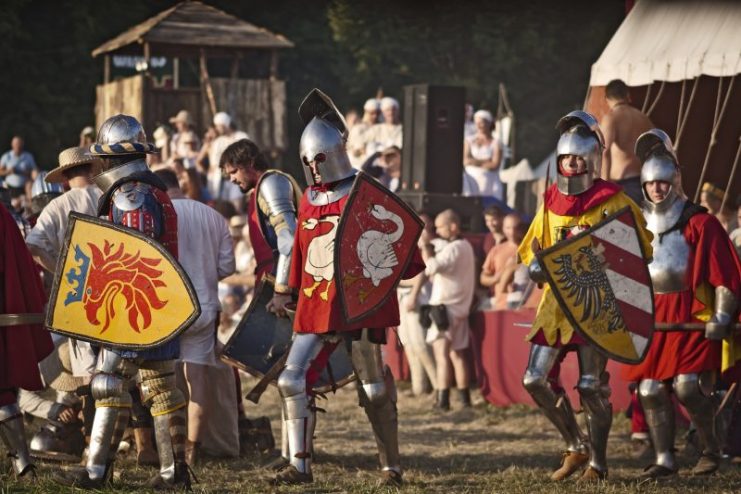 Reenactors dressed as Crusader Knights stand in battle array and prepare to enter a medieval battle which takes place at the annual historical reenactment of The Battle of Grunwald, Poland.