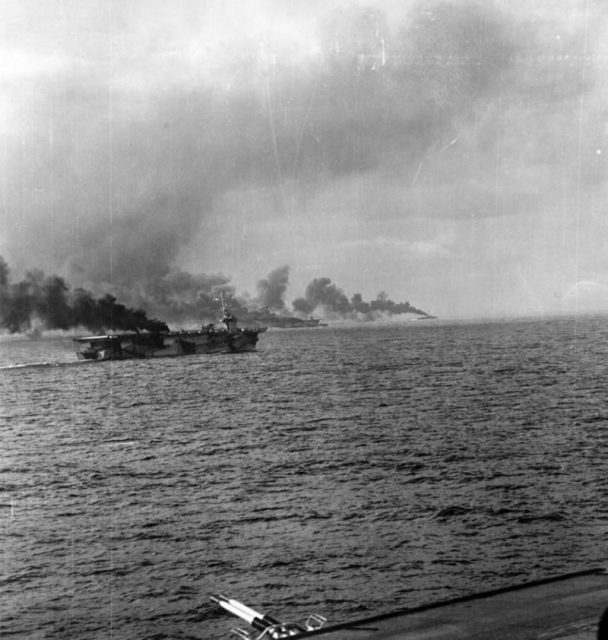 USS Gambier Bay (CVE 73) and another escort carrier, and two destroyer smoke escorts from battle damage during the Battle of Samar on Oct. 25, 1944.