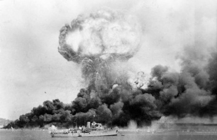 The explosion of a ship, filled with TNT and ammunition, hit during the first Japanese air raid on Australia’s mainland, at Darwin on 19 February 1942. In the foreground is HMAS Deloraine, which escaped damage.