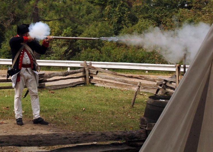 A historical interpreter, fires a flintlock musket during a demonstration.