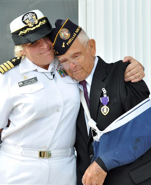 Former Aviation Metalsmith 1st Class Lewis Hopkins, a Battle of Midway survivor, is embraced and presented with Purple Heart.