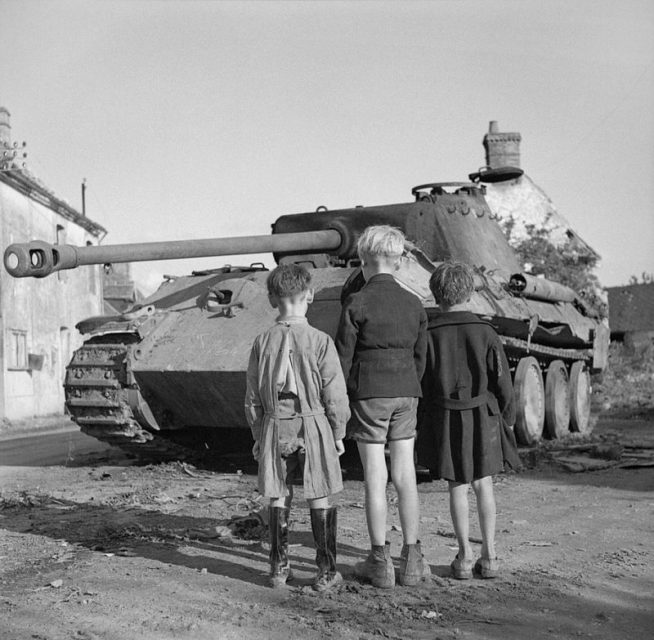 Three French boys looking at a knocked-out German Panther tank in the Falaise pocket, Normandy, 25 August 1944.
