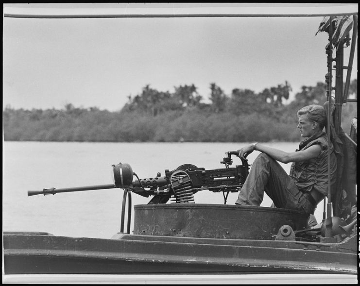 A U.S.Navy river patrol boat (PBR) crewman maintains vigilance at the .50-caliber machine gun