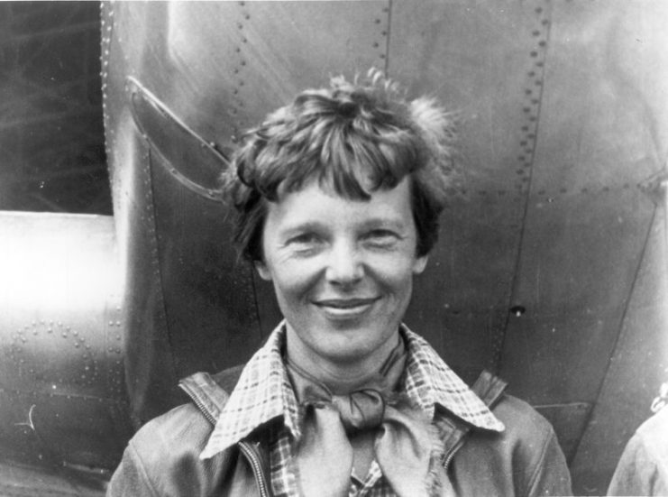 Amelia Earhart standing under nose of her Lockheed Model 10-E Electra.