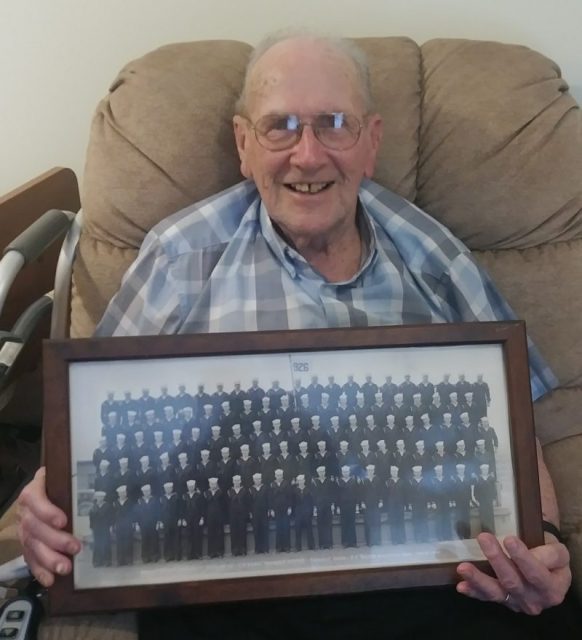 Bernard Heet holds the photograph of his U.S. Navy boot camp graduation class at Farragut, Idaho, in January 1945.The sailor later trained as a signalman and served during WWII aboard a submarine chaser throughout the Pacific Ocean. Courtesy of Jeremy P. Amick.