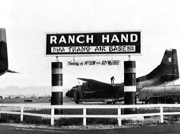 The “Ranch Hand” sign at Nha Trang Air Base, Vietnam, with a Fairchild C-123B Provider in the background. Note the additional sign “Courtesy of 14th SOW and 62nd Wg VNAF”.