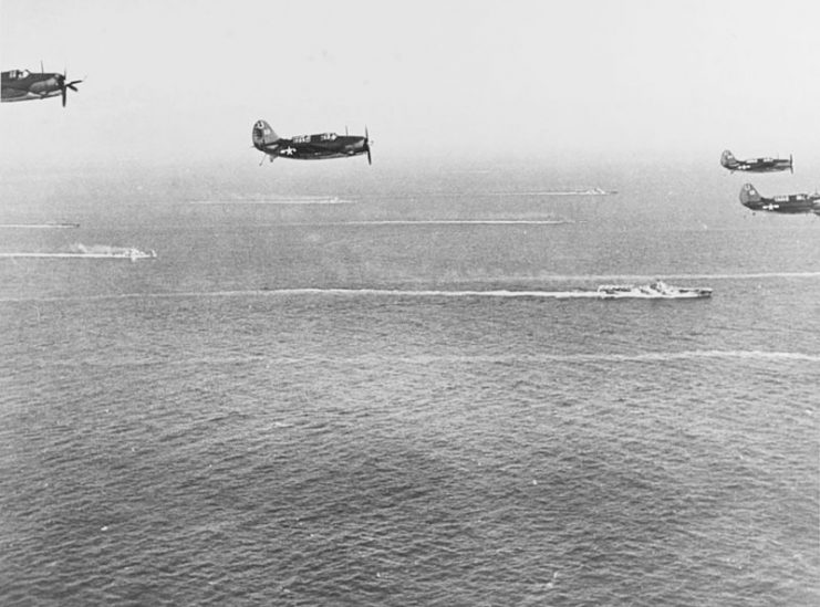 U.S. Navy Curtiss SB2C-3 Helldivers from Bombing Squadron 7 (VB-7) return to the aircraft carrier USS Hancock (CV-19), flying over Task Force 38 on their return from strikes on Manila Bay, 25 October 1944.
