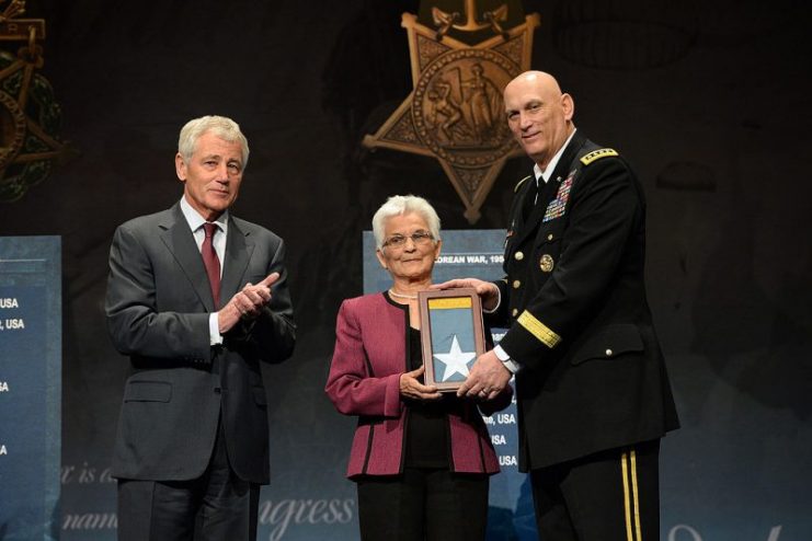 Chief of Staff of the Army, Gen. Raymond T. Odierno, joined by Secretary of Defense Chuck Hagel, presents the Medal of Honor Flag to Alice Mendoza, on behalf of her husband, Staff Sgt. Manuel V. Mendoza, one of 24 Army veterans to receive the flag as part of the Valor 24 Hall of Heroes Induction ceremony at the Pentagon, Washington D.C., March 19, 2014.