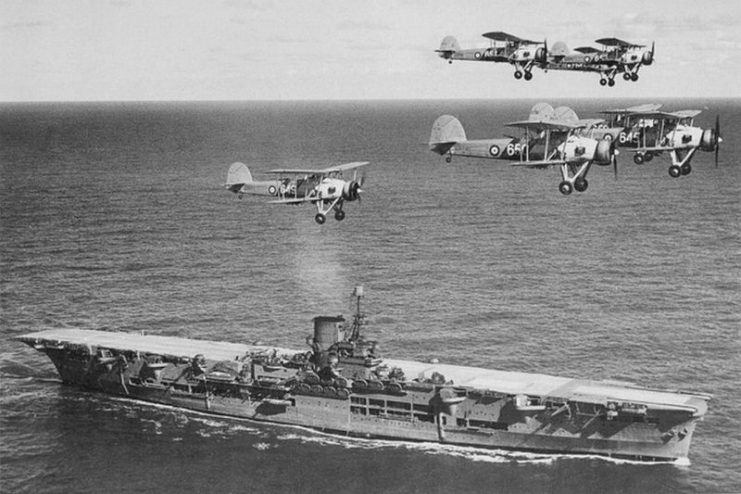 HMS Ark Royal in 1939, with Swordfish of 820 Naval Air Squadron passing overhead. The ship was sunk in 1941