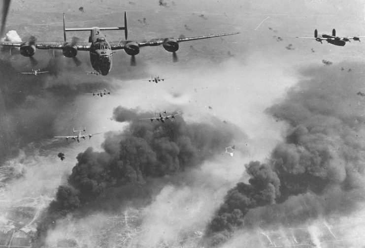 15th Air Force B-24s fly through flak and over the destruction created by preceding waves of bombers.
