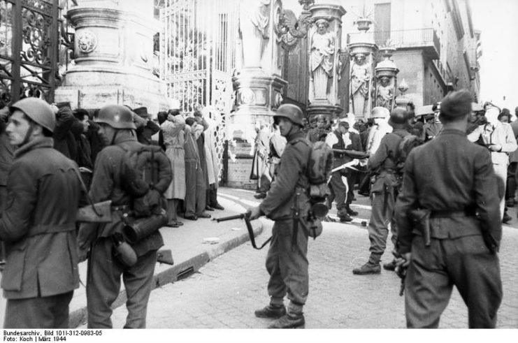 German troops and Italian collaborators round-up of civilians in front of the Palazzo Barberini, Rome, in March 1944. By Bundesarchiv – CC BY-SA 3.0 de