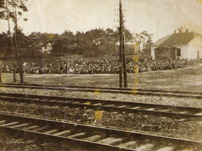 Layover yard in Otwock, August 19, 1942. In the distance, Jews sit on the ground overnight, while awaiting transport to Treblinka extermination camp. Clandestine photo