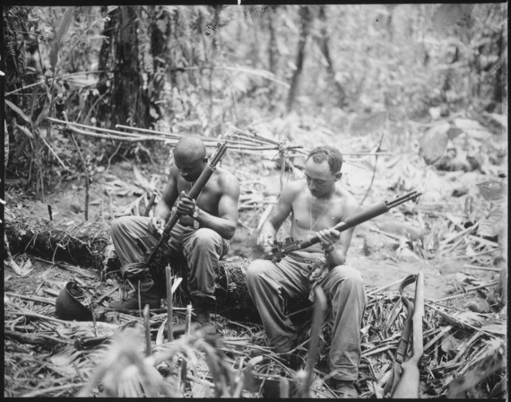 Two soldiers take time to clean their M1 Garands, on Bougainville, April, 1944.