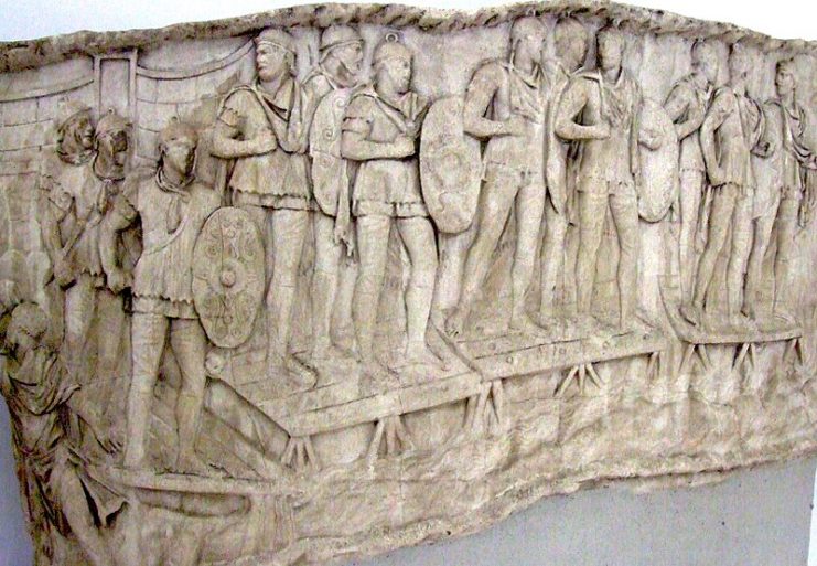 Roman auxiliary infantry crossing a river, probably the Danube, on a pontoon bridge during the emperor Trajan’s Dacian Wars (AD 101–106). They can be distinguished by the oval shield (clipeus) they were equipped with, in contrast to the rectangular scutum carried by legionaries. Panel from Trajan’s Column, Rome.Photo: CristianChirita CC BY-SA 3.0