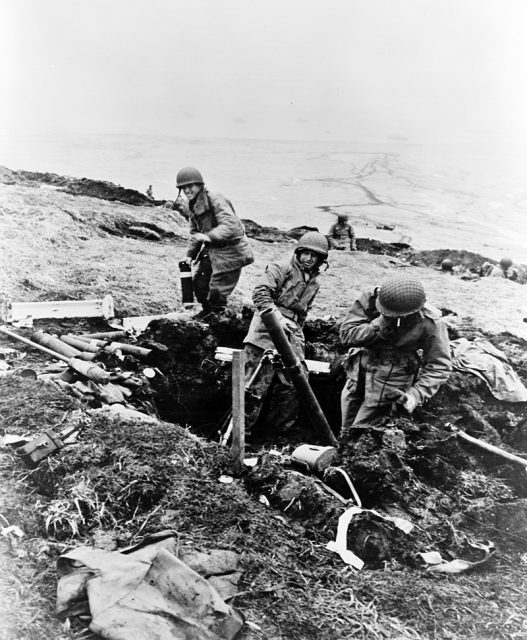 U.S. soldiers fire mortar shells over a ridge onto a Japanese position on 4 June 1943.