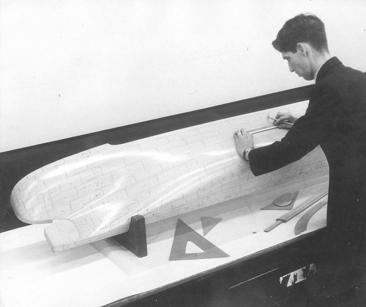 Draughtsman checking measurements of a scale model ship