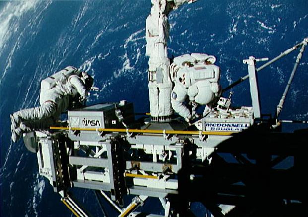 The ASEM is manipulated by the RMS while astronauts Kathryn Thornton and Thomas Akers are on an EVA during STS-49.