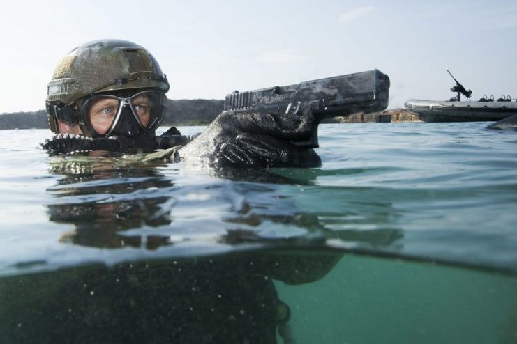 A military diver displaying a Glock 17 fitted with maritime spring cups