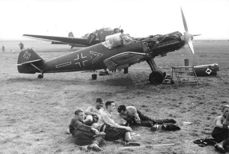 Luftwaffe soldiers of the Jagdgeschwader 53 (JG 53) fighter wing (known as “Ace of Spades”) resting at an airfield infront of a Messerschmitt Bf 109 with an open cowling. Photo: Bundesarchiv, Bild 101I-337-0036-02A / Folkerts / CC-BY-SA 3.0