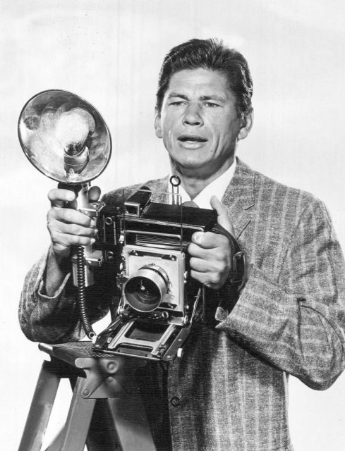 Photo of Charles Bronson as Mike Kovac from the television program Man With a Camera. (Probably a Speed Graphic camera.)