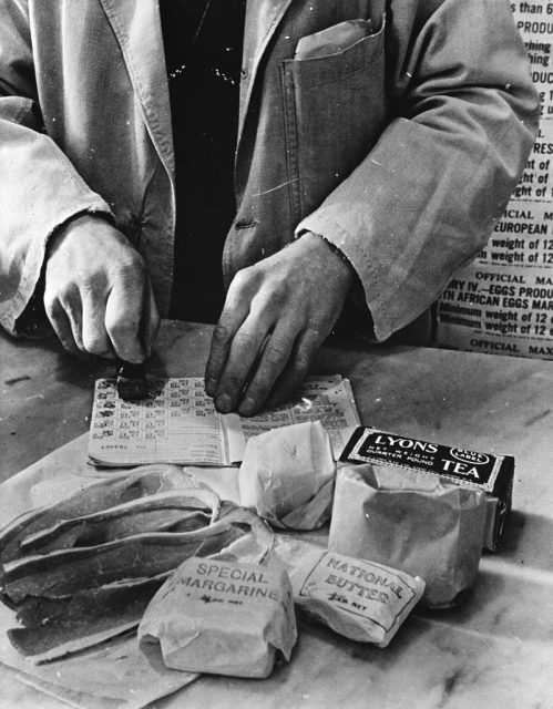 Civilian rationing: A shopkeeper cancels the coupons in a British housewife’s ration book in 1943