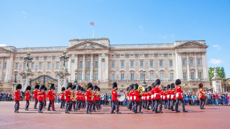 The band of the Grenadier Guards, led by a Drum Major of the Coldstream Guards, marches past the front of Buckingham Palace during the Changing of the Guard ceremony.