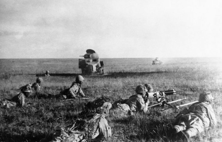 Japanese soldiers creeping in front of wrecked Soviet tanks