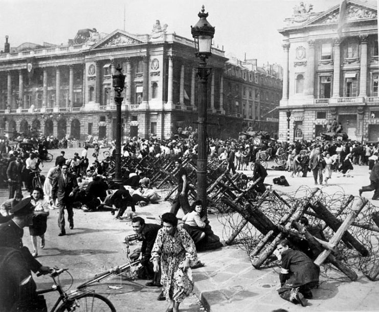 As allied troops enter Paris on August 26, celebrating crowds on place De La Concorde scatter for cover from small bands of remaining German snipers.