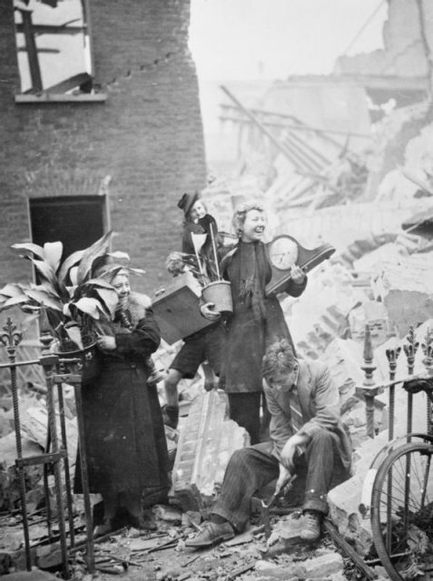 Women salvaging possessions from their bombed house, including plants and a clock