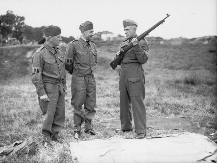A sergeant instructor explaining the working of a rifle to two members of the Local Defence Volunteers at Bisley range.