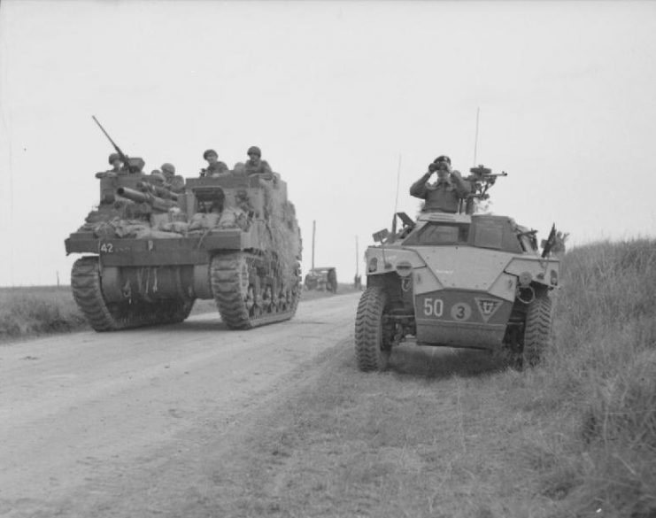 M7 Priest passes by a Humber Scout Car as it moves into position to support an attack on Caen, July 8, 1944.