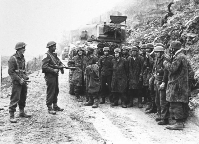 German troops captured by the New Zealanders at Cassino being held beside a Sherman tank.