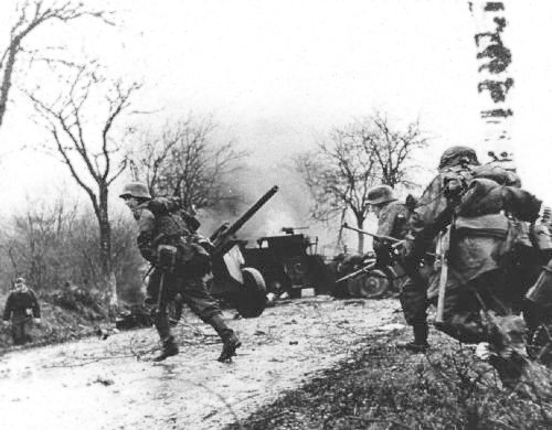 German troops advancing past American equipment at the Battle of the Bulge via commons.wikimedia.org