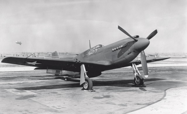 With dive flaps deployed, a new A-36 sits parked on the ramp at NAA in Inglewood. The airplane has yet to be fitted with its weaponry in its wings or nose. In the background we see another famous dive-bomber of World War II—a Douglas SBD Dauntless. Santa Maria Museum of Flight