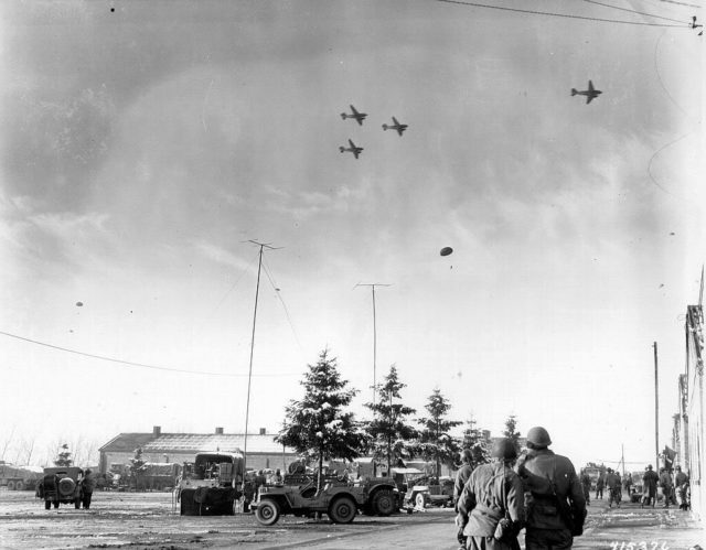 The photo above shows the relief droppings from the C-47s over the surrounded Bastogne pocket. It was one of those C-47’s that did a low fly pass for a dropping on Christmas Eve, 1944 and was shot at by a German light caliber gun.