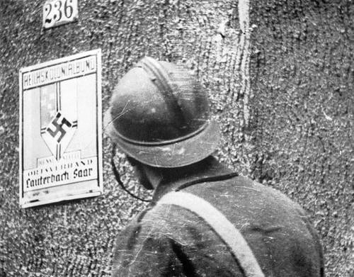 A French soldier examines a German street sign during the Saar Offensive. September 1939 (By Unknown, Probably taken september 1939. - http://www.ww2incolor.com/french/Num__riser0003_001.html, CC BY-SA 3.0 / Wikipedia)