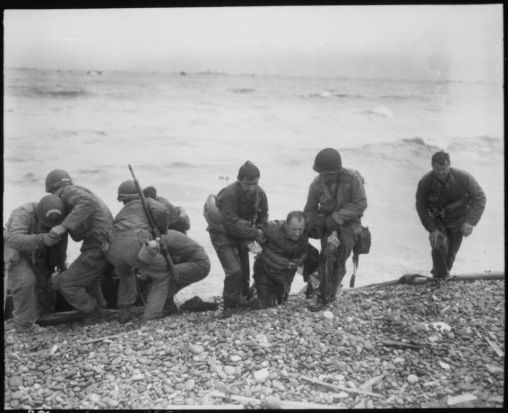 Members of an American landing party lend helping hands to others whose landing craft was sunk by enemy action off Utah.