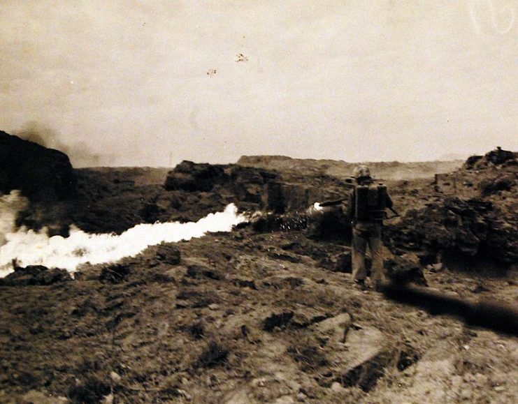 Sergeant Leonard J. Shoemaker, Newberry, Michigan, uses his flame thrower on Japanese caves in mopping up operation on Iwo Jima.