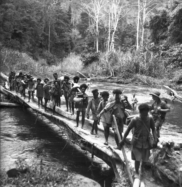 Papuan carriers in Australian service crossing a river between Nauro and Menari in October 1942