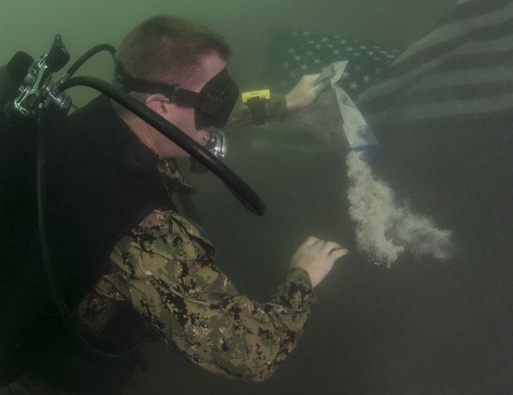 Steel Worker 1st Class Jesse Hamblin, with Underwater Construction Team (UCT) 2 Construction Dive Detachment (CDD) Alpha, spreads the ashes of his grandfather, WWII veteran Donald Booth, at the USS Arizona Memorial in Pearl Harbor.