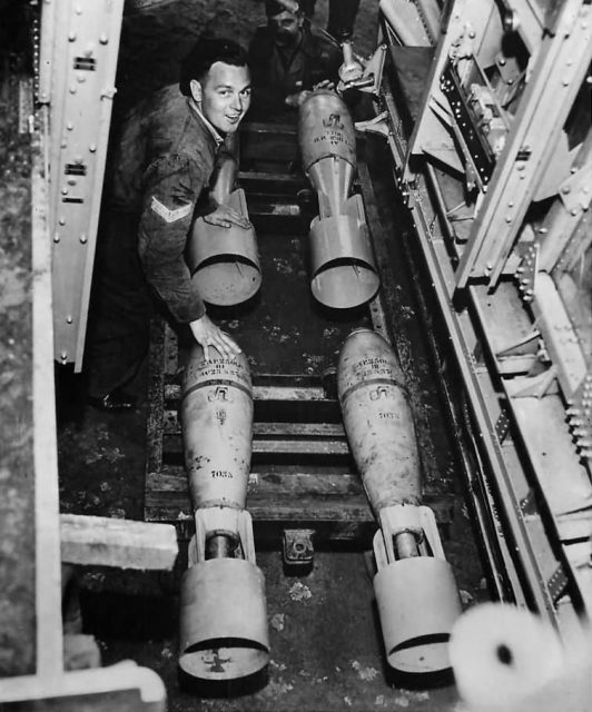 View thru bomb bay as ground crew loads bombs on B-17
