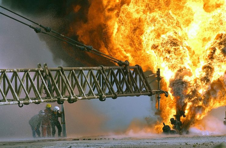 Kuwaiti firefighters fight to secure a burning oil well in the Rumaila oilfields, set ablaze by Iraqi military forces